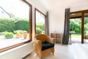 uma cadeira de vime num quarto com uma janela em RAJ Living - 6 Room Villa with Garden - 15 Min Messe DUS & Airport DUS em Meerbusch