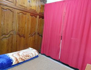 a bedroom with a red curtain next to a bed at Appartement Hamria RiF in Meknès