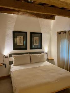 1 dormitorio con 1 cama blanca y 2 cuadros en la pared en La Corte del Gusto LuxuryApartments, en Arcevia