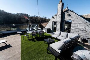 eine Terrasse mit Sofas und Tischen sowie ein Gebäude in der Unterkunft Les 3 chapeaux Dinant in Dinant