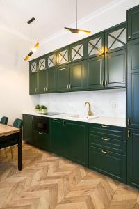 a kitchen with green cabinets and a wooden floor at Glamorous Apartment Old Town Cracow in Krakow