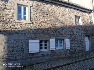 a stone building with two windows and white shutters at Le Terrier du Lapin Blanc in Saint-Brieuc