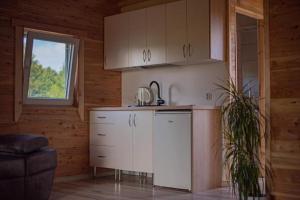 a kitchen with white cabinets and a window at Domek Pod Świerkami in Sorkwity