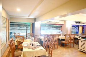 a dining room with tables and chairs and windows at Hotel Sagar in Kalyan
