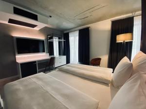 Cette chambre comprend un grand lit et une télévision. dans l'établissement DORMERO Hotel Aschaffenburg, à Aschaffenbourg