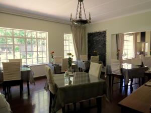 a dining room with a table and chairs and windows at Bordeaux Haven Guest House in Vereeniging