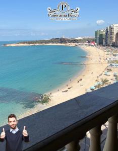 a man in a suit giving the thumbs up next to a beach at شقق بانوراما شاطئ الأسكندرية كود 4 in Alexandria