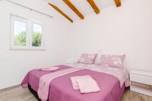 a white bedroom with a large bed with pink sheets at Apartments Dubrovnik Airport in Čilipi