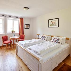 a bedroom with a large white bed with two chairs at Hotel Hof Tütsberg in Behringen