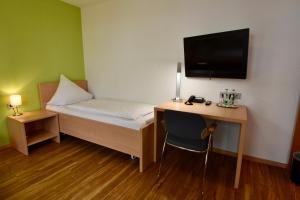 Cette petite chambre comprend un bureau, un lit et une télévision. dans l'établissement Hotel Kranz, à Gottmadingen