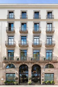 バルセロナにあるDuquesa de Cardona Hotel 4 Sup by Duquessa Hotel Collectionの窓とバルコニー付きの白い大きな建物