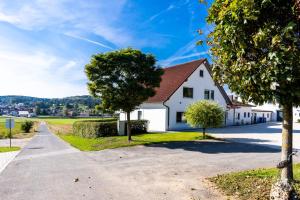 a white house with a tree on the side of a road at Jura Ferienhof in Velburg