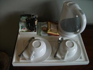 a tray with two plates and a tea pot and spoons at The Bull Inn Lodges in Tenterden