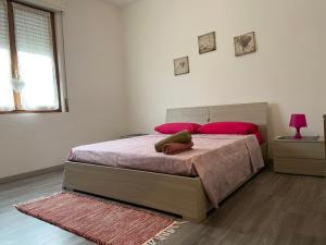 - une chambre avec un lit doté de draps roses et d'oreillers rouges dans l'établissement Casa Do Sol Apartment, à Peschiera del Garda