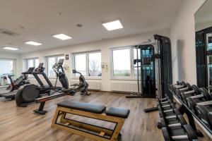 a gym with treadmills and ellipticals in a room at Waldhotel zum Bergsee Damme in Damme