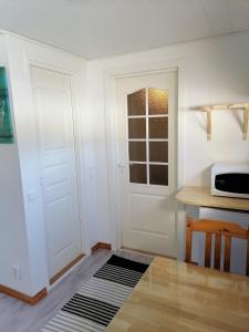 eine Küche mit einer Tür, einem Tisch und einer Mikrowelle in der Unterkunft Hostel Mansikka in Taipalsaari
