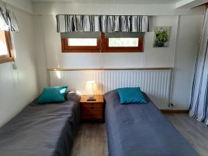 two beds in a small room with blue pillows at Hostel Mansikka in Taipalsaari
