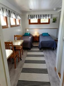 Habitación pequeña con 2 camas y mesa. en Hostel Mansikka en Taipalsaari