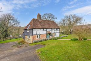 uma casa velha num campo com uma entrada em Bellflower Cottage, Ashdown Forest em Horsted Keynes