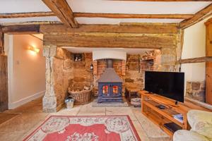 a living room with a fireplace and a tv at Bellflower Cottage, Ashdown Forest in Horsted Keynes