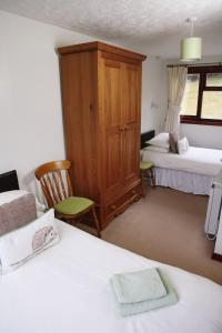 a bedroom with two beds and a wooden cabinet at Ardgarry Farm in Invergarry