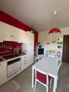 cocina con mesa blanca y pared roja en Da Felicia, en Cossato