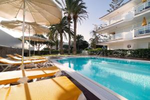 basen z krzesłami i parasolami obok budynku w obiekcie Apartamentos Montemayor w mieście Playa del Ingles