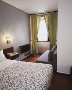 um quarto de hotel com uma cama, um sofá e uma janela em Hotel Jardim Viana do Castelo em Viana do Castelo