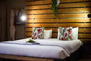 een slaapkamer met een houten muur en een bed met kussens bij De Akker Guest House Oudtshoorn in Oudtshoorn