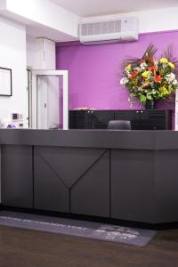 a reception desk with a vase of flowers on a purple wall at Hotel du Chemin Vert in Paris