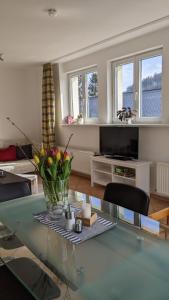 una sala de estar con una mesa de cristal con flores. en Residenzpark Willingen Haus Langenberg en Willingen