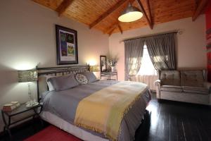 a bedroom with a bed and a chair and a window at Thulamela Couples Retreat in Hazyview