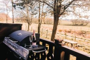 a grill with a glass of wine on a table at Keer Side Lodge, Luxury lodge with private hot tub at Pine Lake Resort in Carnforth