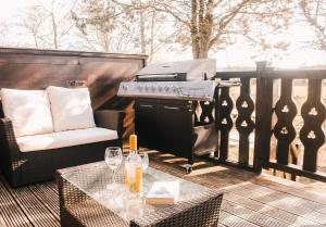 a grill on a deck with a chair and a table at Keer Side Lodge, Luxury lodge with private hot tub at Pine Lake Resort in Carnforth