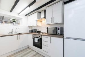 een witte keuken met witte kasten en apparaten bij ✰Excellent 3 bedroom House - Close To Airport in Castle Donington