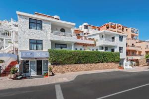 ein großes weißes Gebäude mit einer Mauer neben einer Straße in der Unterkunft Apartamentos NataLis in Morro del Jable