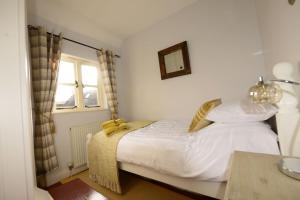 a bedroom with a bed with white sheets and a window at Victoria Cottage, Ironbridge in Ironbridge