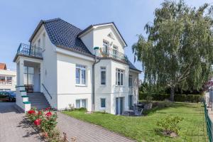 ein weißes Haus mit einem Zaun davor in der Unterkunft Doberaner Straße 15 Wohnung 02 in Kühlungsborn