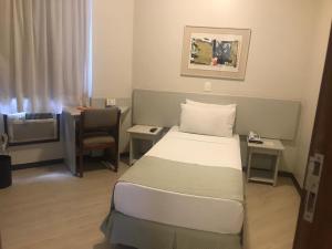 a hotel room with a bed, desk and a lamp at Boulevard Express in Belo Horizonte