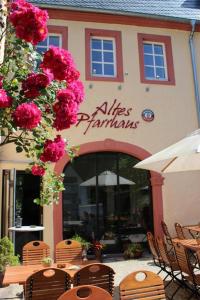 un restaurante con mesas, sillas y flores rosas en Altes Pfarrhaus 