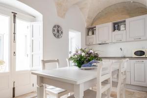 a white kitchen with a white table and chairs at Palazzo Rapanà - Luxury Apt with hydromassage pool in Ostuni