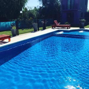 a blue swimming pool with two benches next to it at Un lugar en Monte in San Miguel del Monte