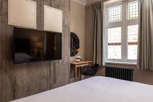 a bedroom with a bed and a tv on a wall at The Fleece Hotel Richmond in Richmond