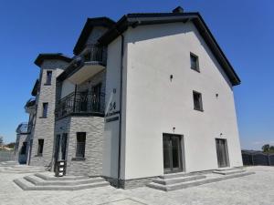biały budynek z czarnym dachem w obiekcie POKOJE GOŚCINNE AZALIOWA 34 Mielno w mieście Mielno