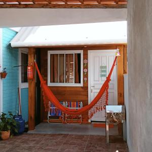 Tiny House moçambique - Sua casinha em Floripa! في فلوريانوبوليس: شرفة مع أرجوحة برتقالية أمام المنزل