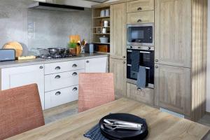 a kitchen with white cabinets and a table with chairs at Captivating Bluebell Lodge 2-bed Cotswolds caravan in Cirencester
