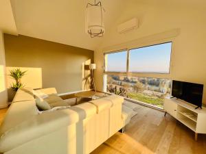 a living room with a white couch and a television at résidence belle vue in Fontaine-le-Port