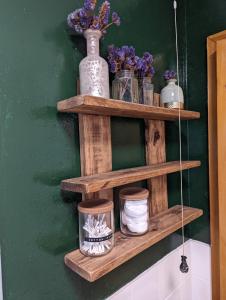 a wooden shelf with jars and flowers on a green wall at Cosy 2-Bed Property in Ashburton Dartmoor in Newton Abbot