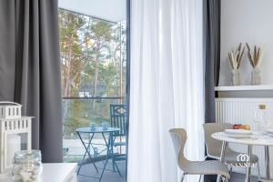 a room with a window with a table and chairs at Apartament Baltic Dune - Pinea Apartments Pobierowo in Pobierowo