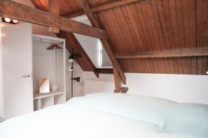 een slaapkamer met een wit bed en houten plafonds bij Sfeervol vakantiehuis in centrum Yerseke in Yerseke +60 foto's